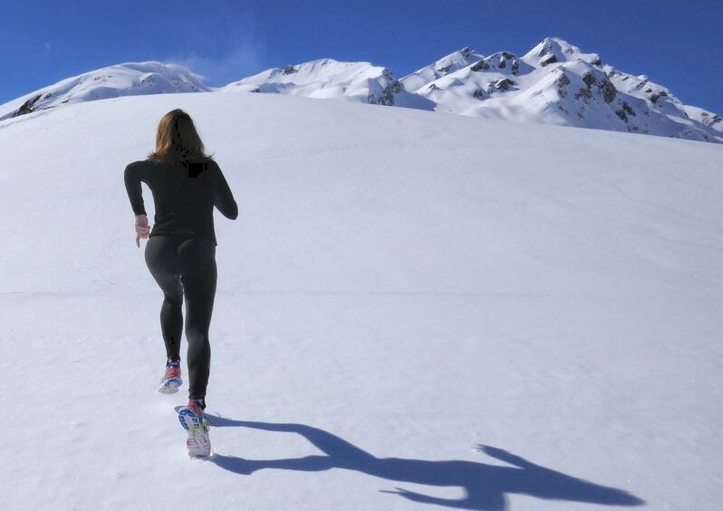 Woman running on snow-capped mountain